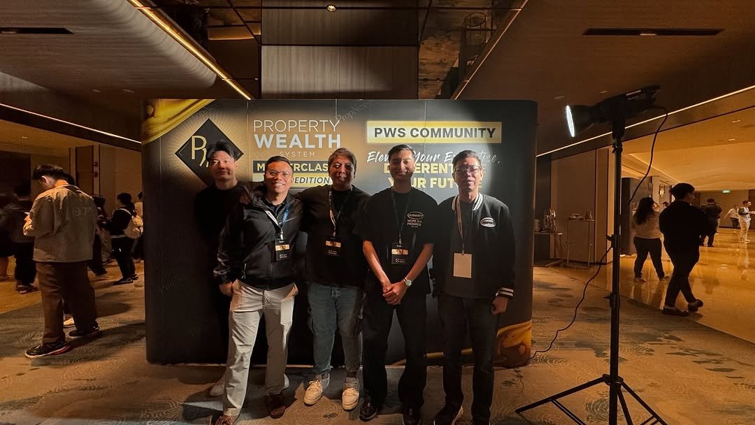 Group of five professionals at a real estate conference, posing in front of a "Property Wealth System Masterclass" banner, showcasing educational initiatives in Singapore's real estate market.